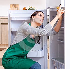 Young woman cleaning fridge in hygiene concept