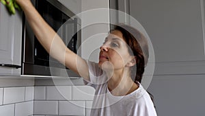 Young woman is cleaning the furniture in the kitchen.