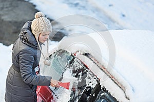 Young woman cleaning her car from snow and frost