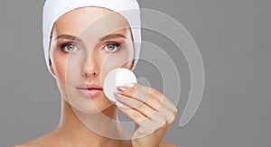 Young woman cleaning her face with a cotton pads. Girl removing cosmetics with hygienic discs.