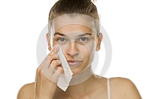 Young woman cleaning her face with wet wipe
