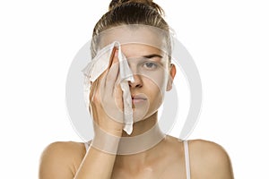 Young woman cleaning her face with wet wipe