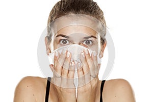 Young woman cleaning her face with wet wipe