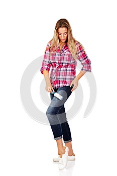 Young woman cleaning her shirt with lint roller