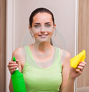 Young woman cleaning mirror at home
