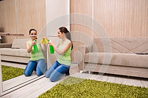 The young woman cleaning mirror at home