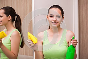 The young woman cleaning mirror at home