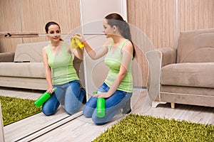 The young woman cleaning mirror at home