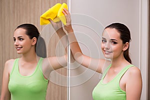 The young woman cleaning mirror at home