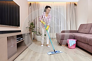 young woman cleaning and mopping floor at living room