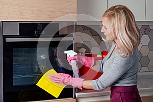 Young woman cleaning oven in the kitchen photo