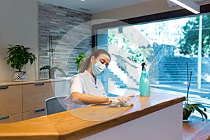 Young woman cleaning reception of spa center