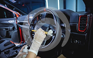 Young woman cleaning the steering wheel of car using a special brush with foam