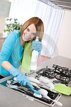 Young woman cleaning stove in kitchen