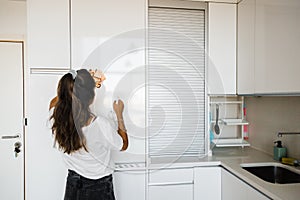 young woman cleaning white and bright kitchen