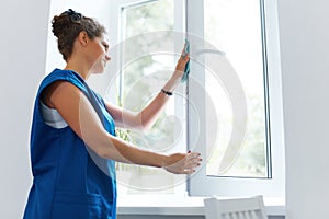 Young Woman cleaning window glass. Cleaning Company Worker