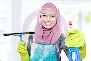 Young woman cleaning windows with squeegee and cleaning spray