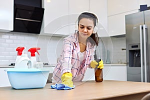 young woman cleaning wooden table with microfiber cloth.