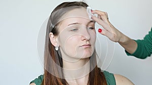 Young woman cleans her face before makeup with a cotton pad making makeup