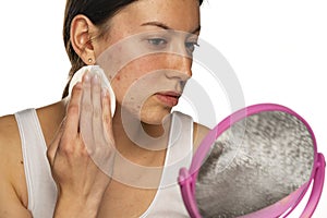 A young woman cleans her face with problematic skin