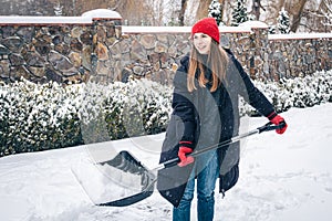 Young woman cleans snow in the yard in snowy weather.