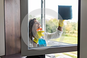 A young woman cleans the window. Rubber gloves on her hands. For cleaning using cleaning fluid and cloth