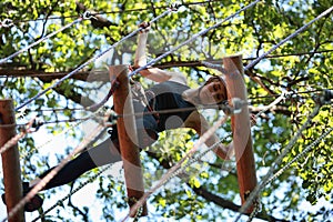 Young woman climbing in adventure rope park