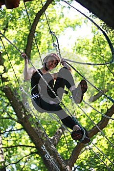 Young woman climbing in adventure rope park