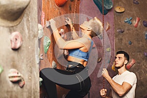 Young woman climbing artificial rock wall at gym