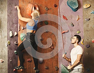 Young woman climbing artificial rock wall at gym