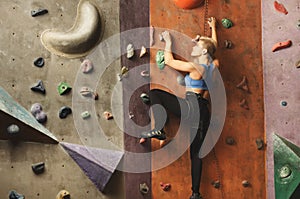 Young woman climbing artificial rock wall at gym