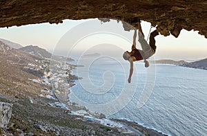 Young woman climbing in cave at sunset