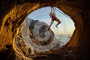 Young woman climbing challenging route in cave with beautiful sea view