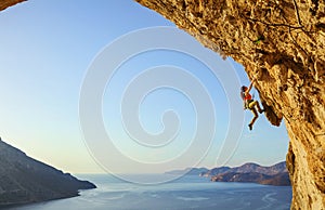 Young woman climbing challenging route in cave at sunset