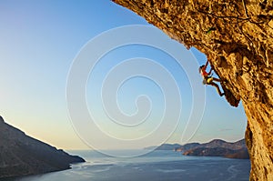 Young woman climbing challenging route at sunset