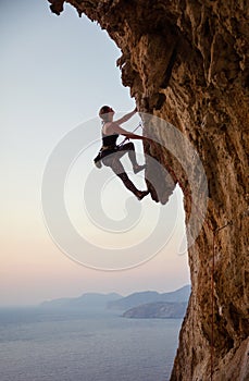 Young woman climbing challenging route at sunset photo