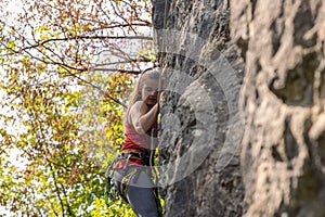 A Young woman climbing on the high rock in the mountains