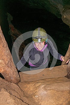 Young woman climbing ladder inside cave