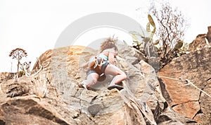 Young woman climbing a rock wall in a canyon - Strong climber training outdoor - Travel, adrenaline and extreme dangerous sport