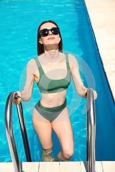 Young woman climbing  pool ladder on sunny day