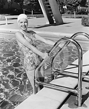 Young woman climbing up the ladder of a swimming pool photo