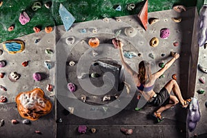 Young woman climbing up on practice wall