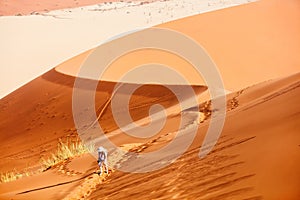 Young woman climbing up red sand dune