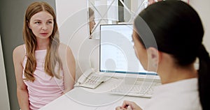 Young Woman at Clinic Reception Discussing Health Concerns