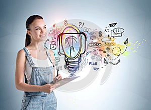 Young woman with clipboard standing over colourful light bulb on a concrete wall