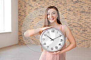 Young woman with clock indoors. Time management concept