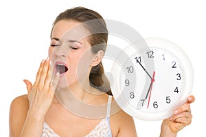 Young woman with clock yawing after sleep photo