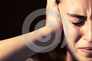 A young woman close-up with headache on black background. Mental illness concept