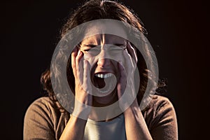 A young woman close-up screaming on black background. Mental illness concept