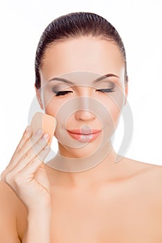 Young woman with closed eyes evens skin tone of her face